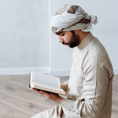 An open Qur'an resting on a wooden stand, pages turned midway