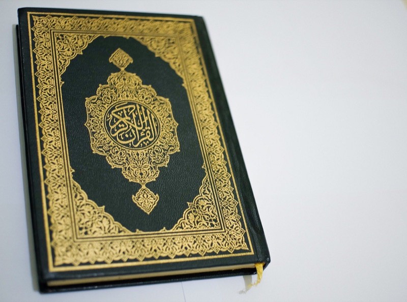 A closed mushaf bound in dark green with gold embossing on the cover