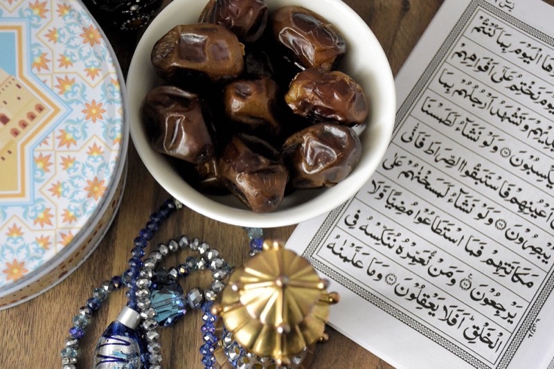 A bowl of dates, a tasbih and an open mushaf laid out for iftar